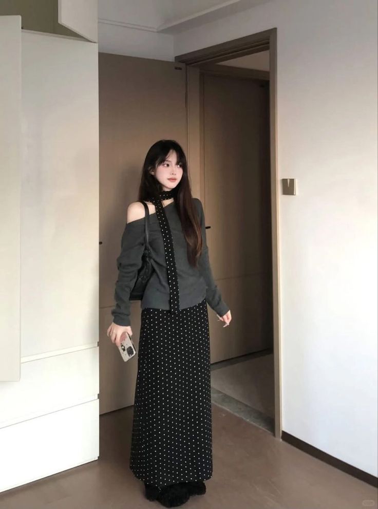 Woman with long hair wearing an off-shoulder top and polka dot skirt indoors