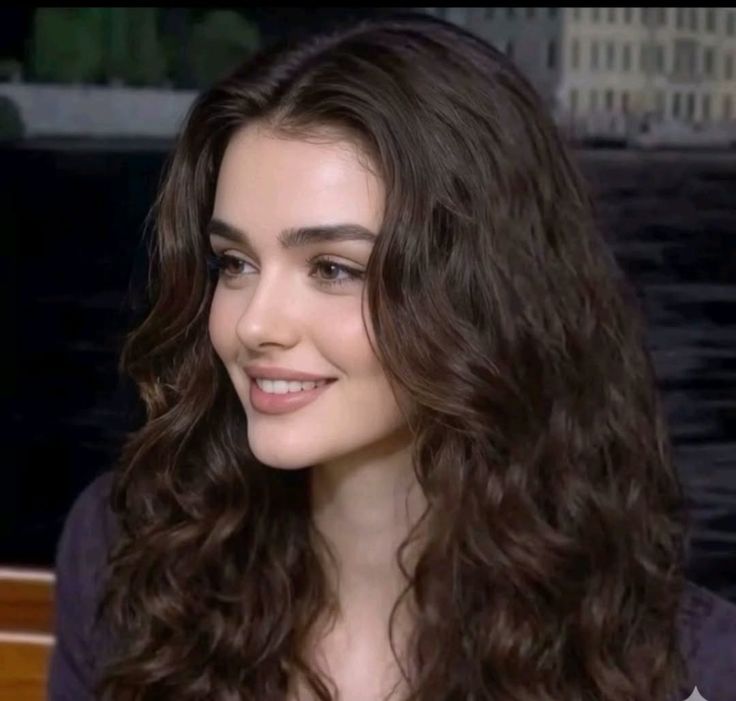 Woman with long wavy dark hair smiling outdoors