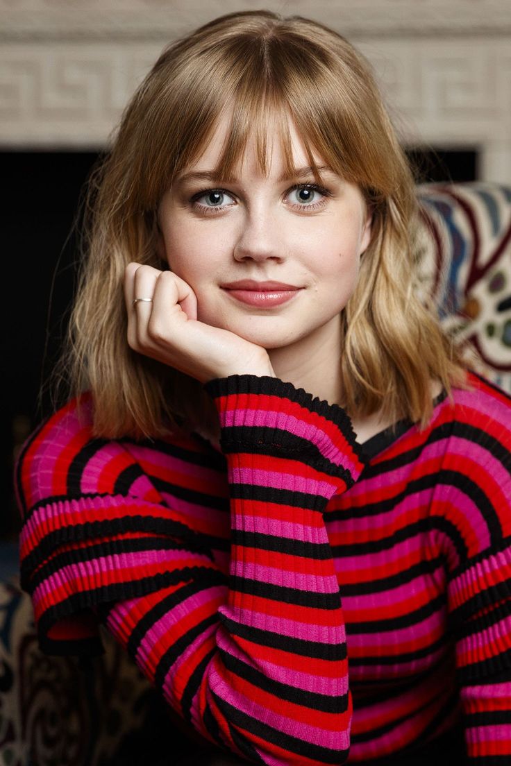 Woman with blonde hair and bangs wearing a red and pink striped shirt