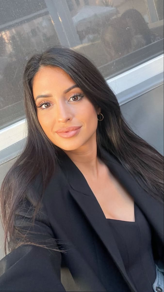 Woman with long black hair wearing a black blazer and hoop earrings