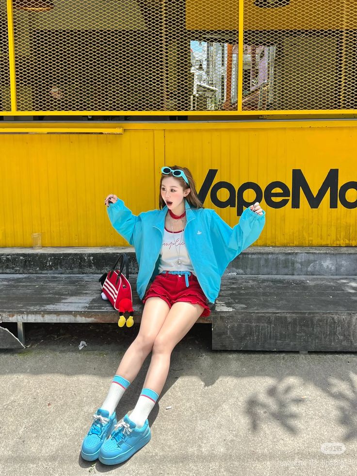 Woman in red shorts and a blue jacket sitting on a bench outdoors