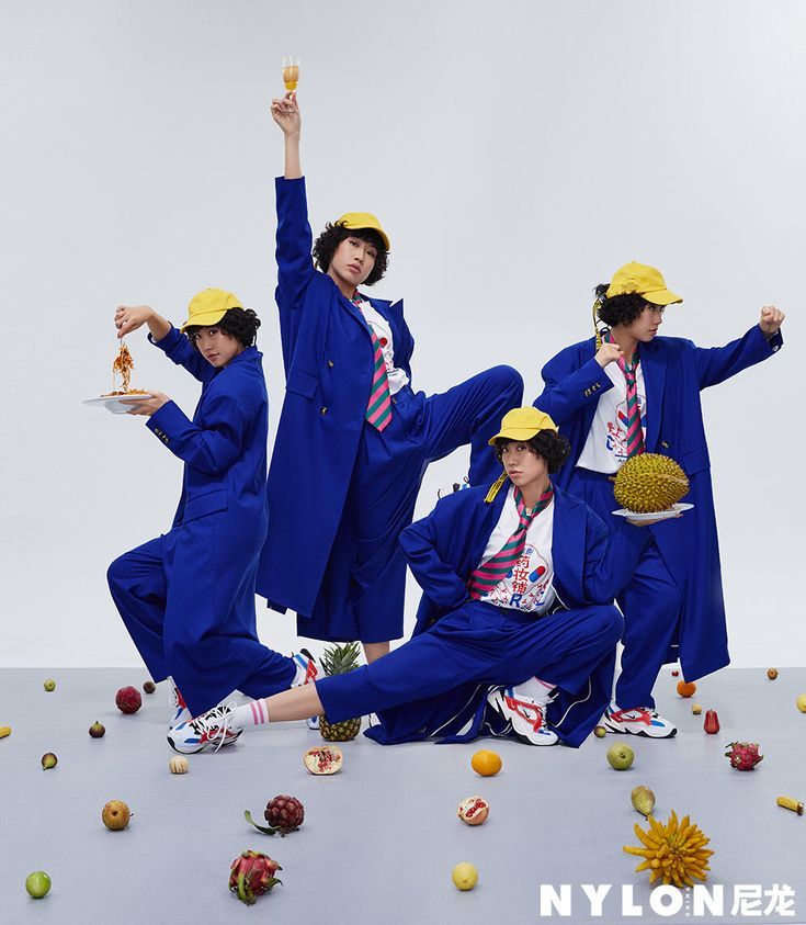 Multiple people in blue suits and yellow caps posing with fruit and food