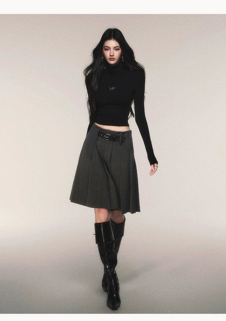 Woman with long black hair wearing a black turtleneck and pleated skirt