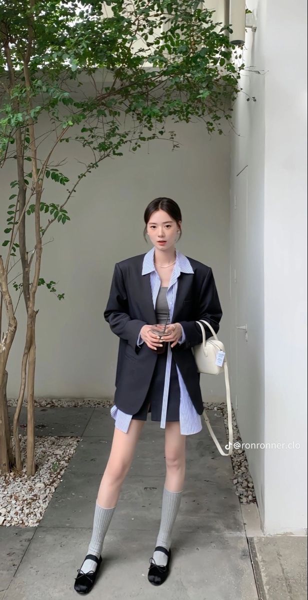Woman in an oversized blazer and striped shirt with a short skirt and knee socks