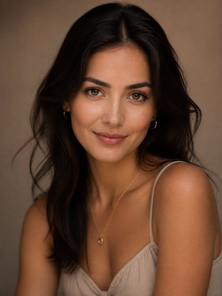 Woman with long dark hair wearing a spaghetti strap top and gold jewelry