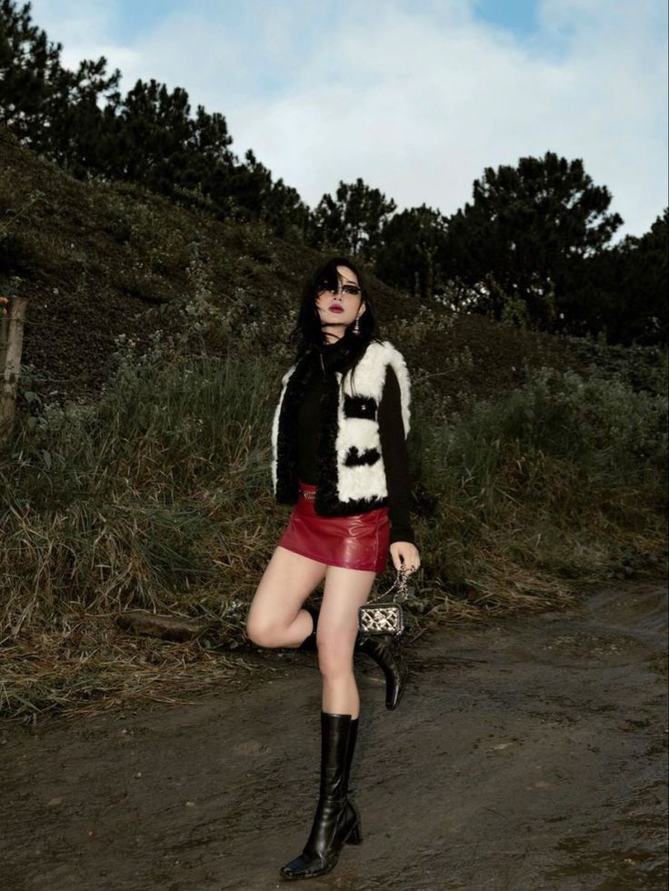 Woman in a red leather skirt and fur vest posing outdoors