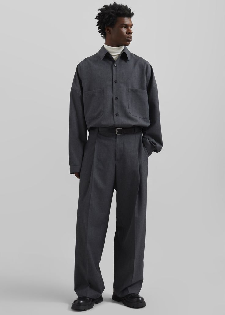Man in a dark gray shirt and wide leg pants with a white turtleneck