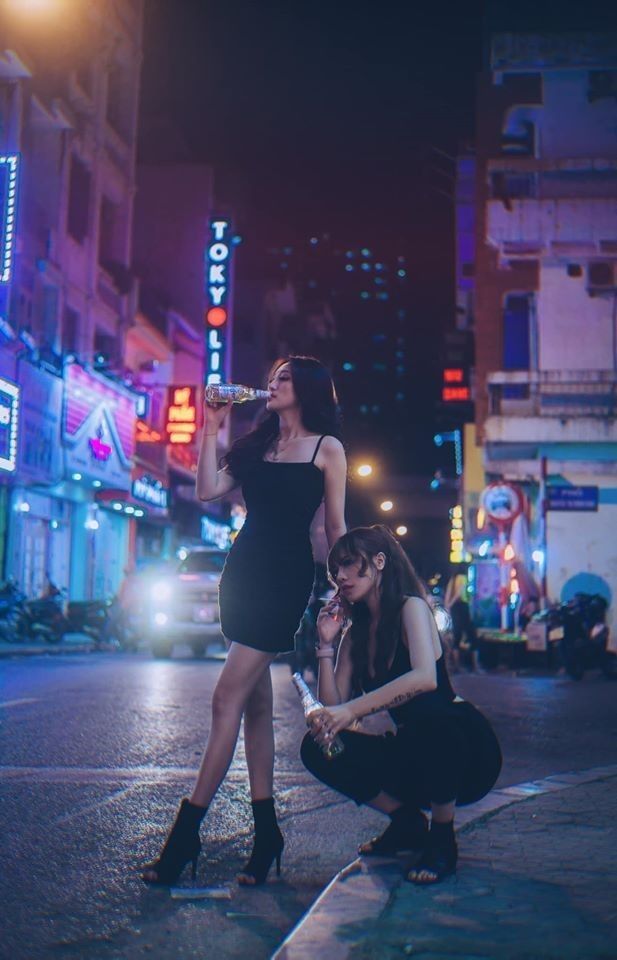 Two women on a neon-lit city street at night