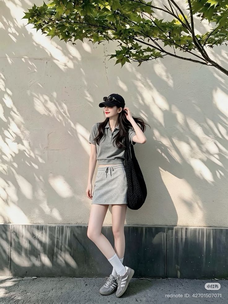 Woman in a gray polo shirt and mini skirt with a baseball cap and sunglasses