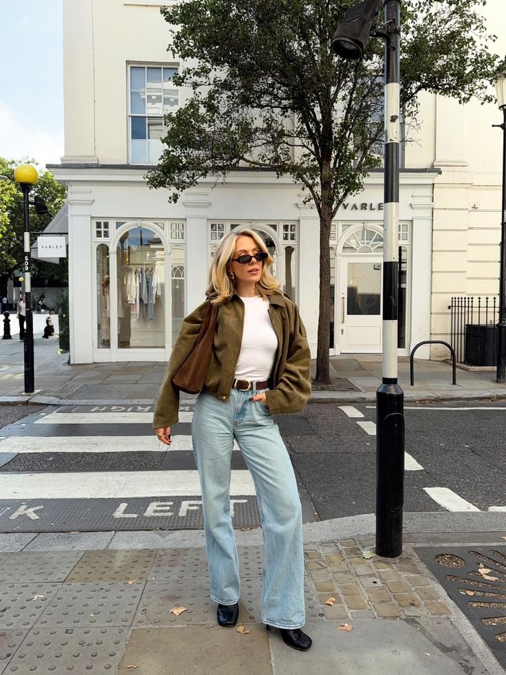 Woman with blonde hair wearing a cropped jacket and wide leg jeans on a city street