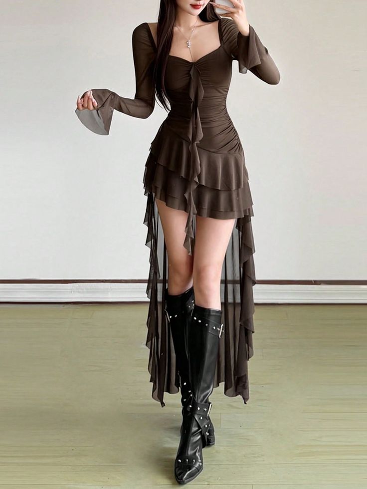 Woman in a dark ruffled dress and black studded boots posing indoors