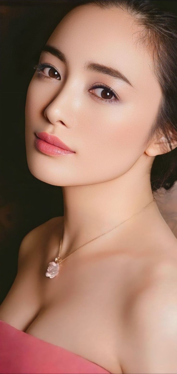 Woman with a necklace and visible cleavage against a dark background