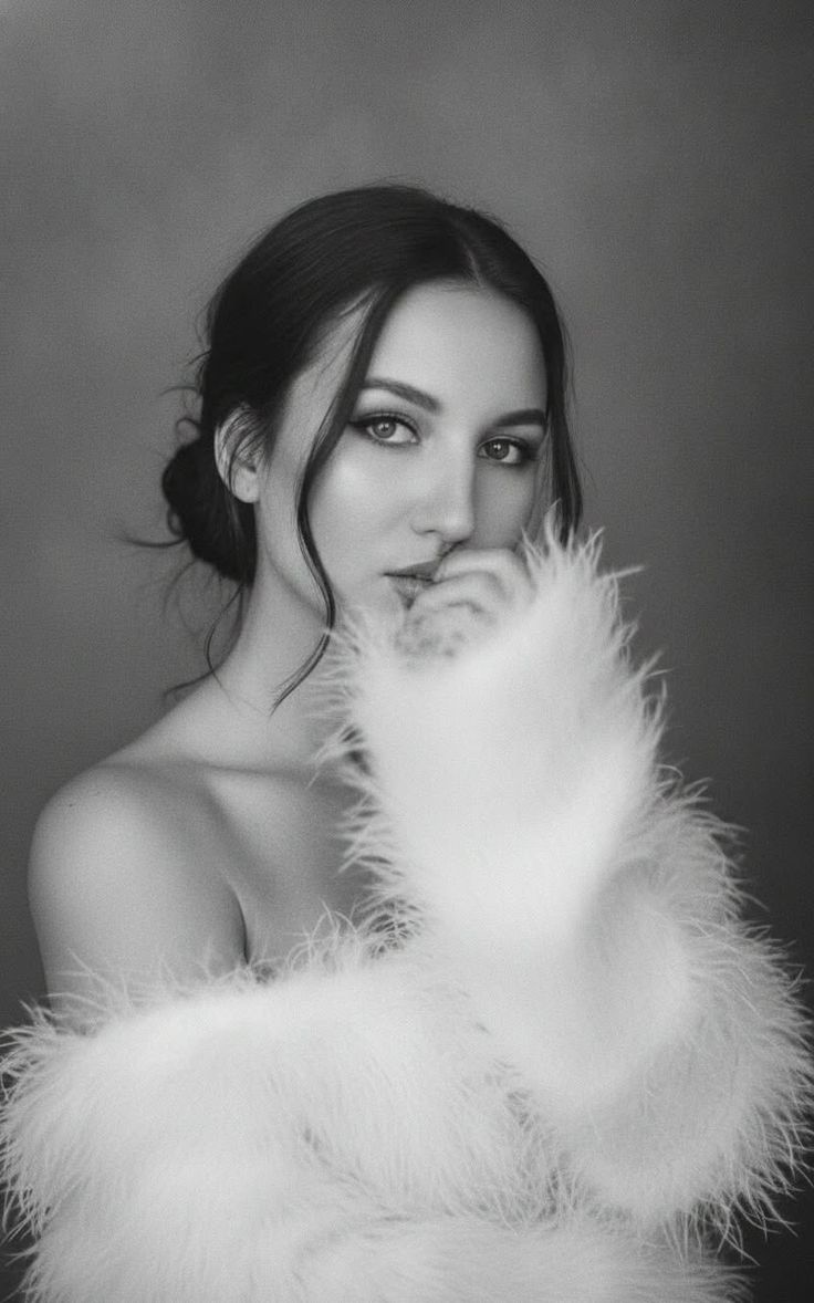 Woman in a white feather boa with dark hair in a black and white portrait
