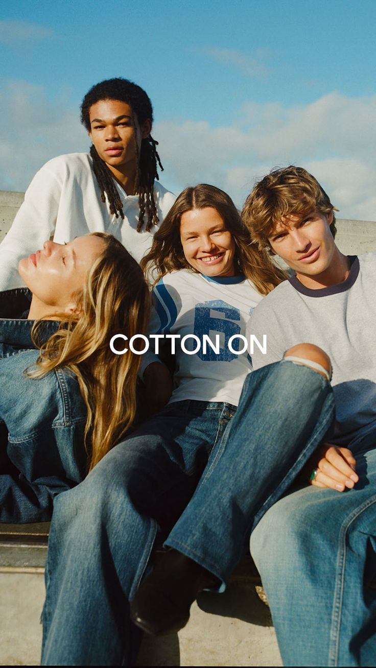 Four young adults in casual clothing sitting outdoors under a blue sky