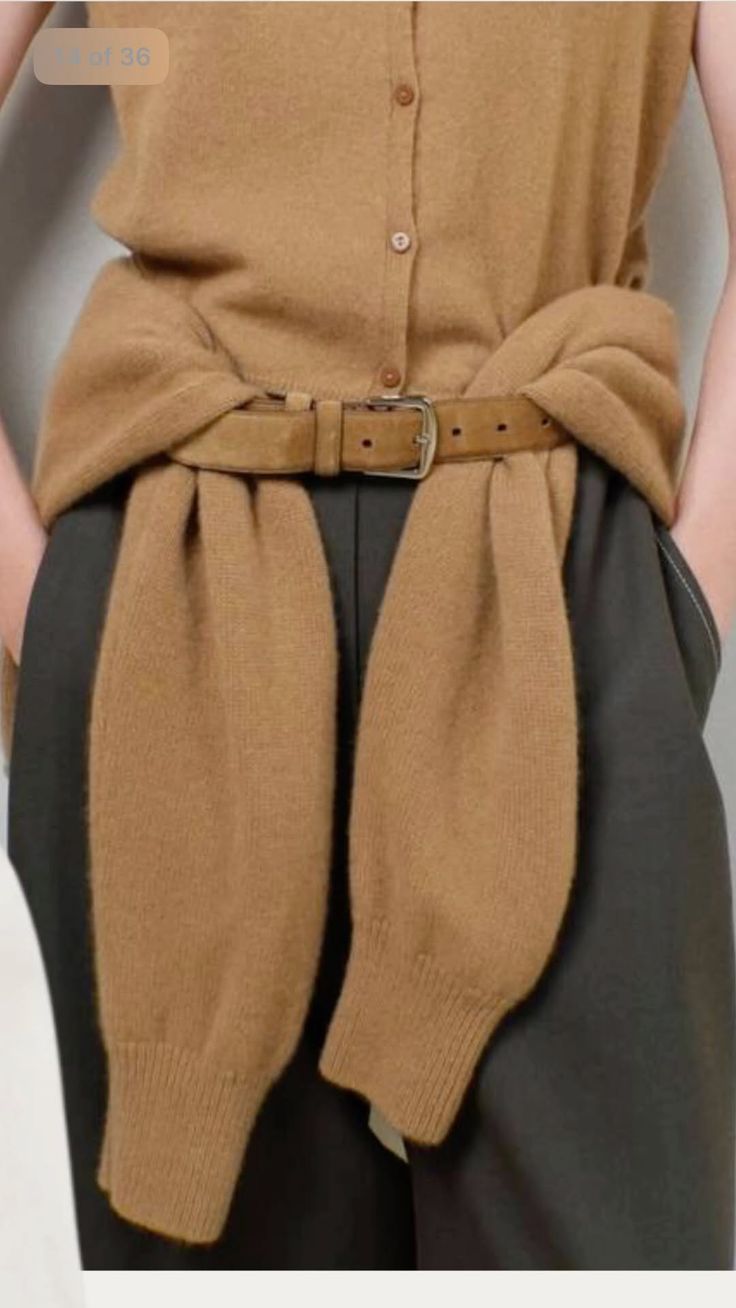 Person wearing a brown cardigan, belt, and dark pants