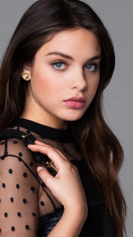 Woman with long brown hair and blue eyes wearing a black polka dot top