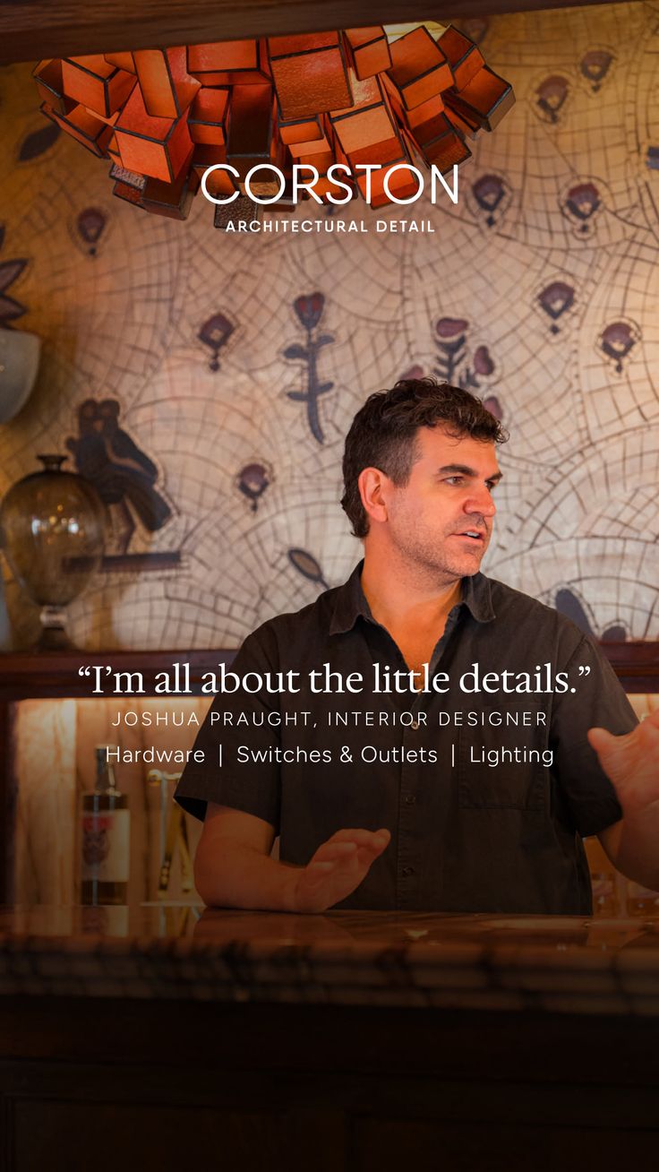 Man in a dark shirt speaking indoors with architectural details in the background