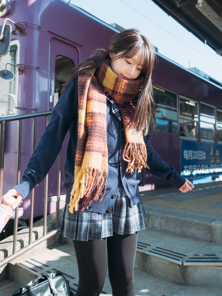 Young woman in a school uniform and plaid scarf at a train station