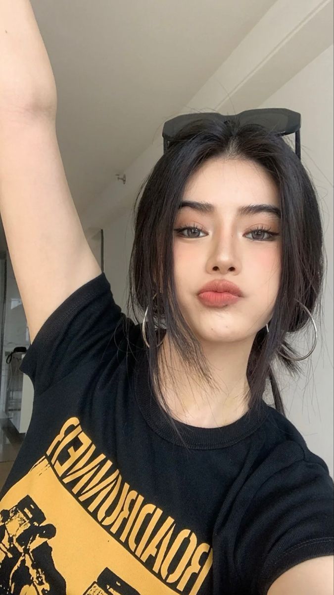 Woman with black hair and hoop earrings wearing a black t-shirt, pouting at the camera