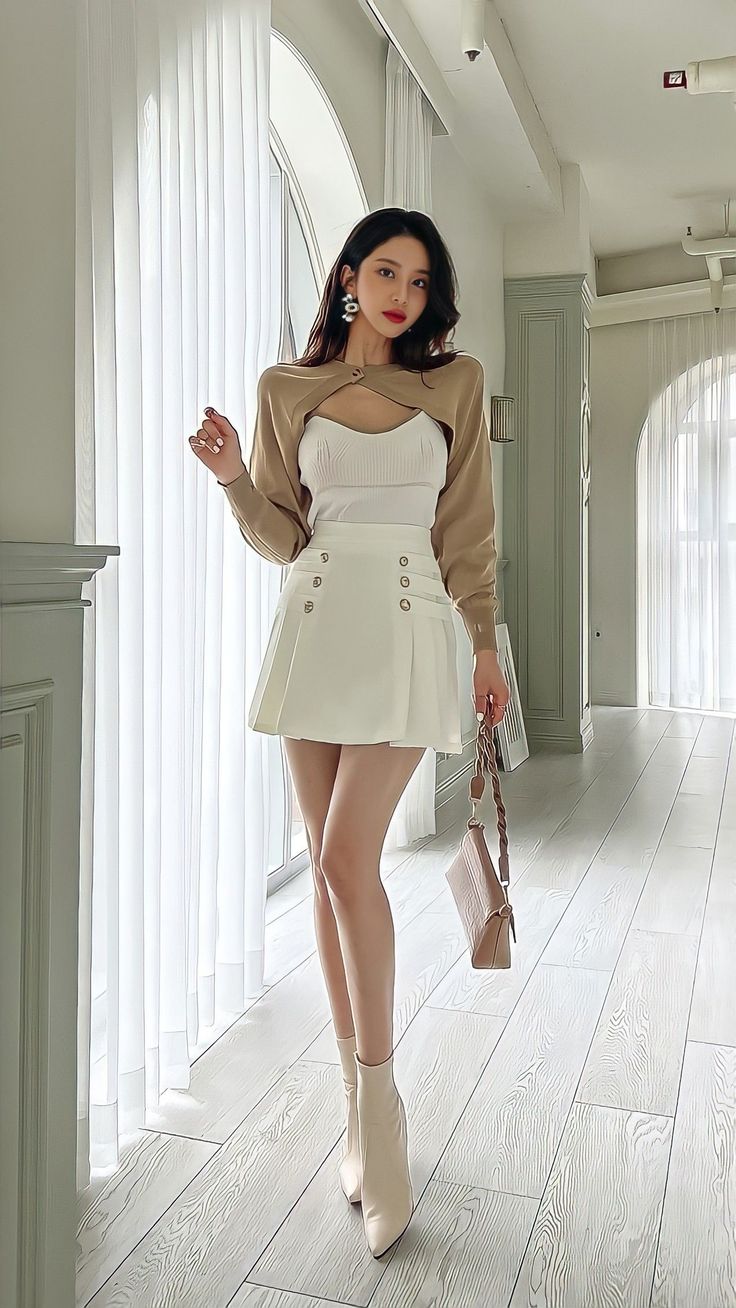 Woman in a white mini skirt and cropped cardigan posing indoors