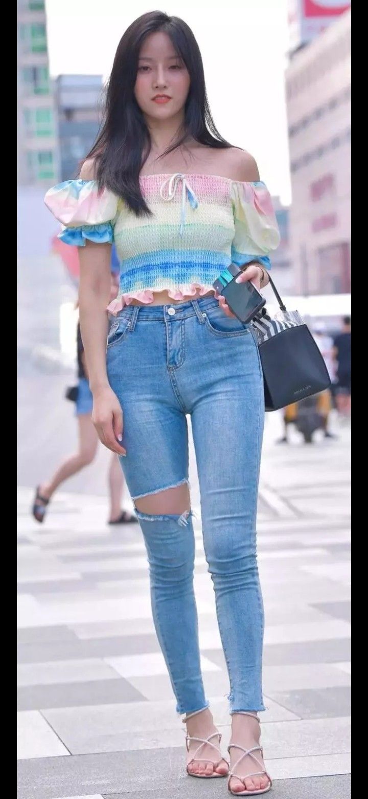 Woman in an off-shoulder top and ripped jeans on a city street