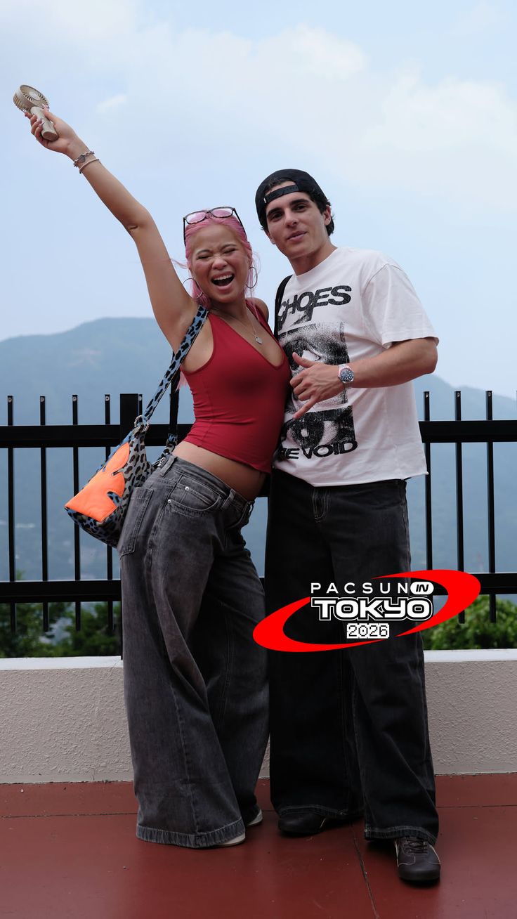 Two people posing outdoors with mountains in the background
