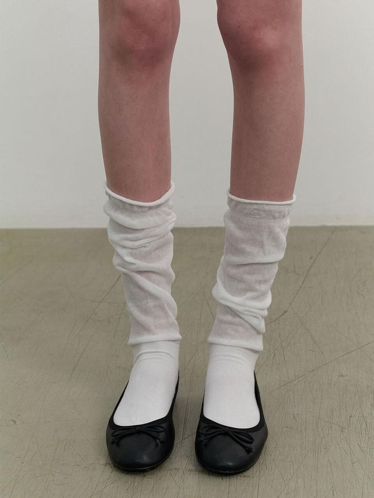 Legs wearing white socks, ruched leg warmers, and black ballet flats
