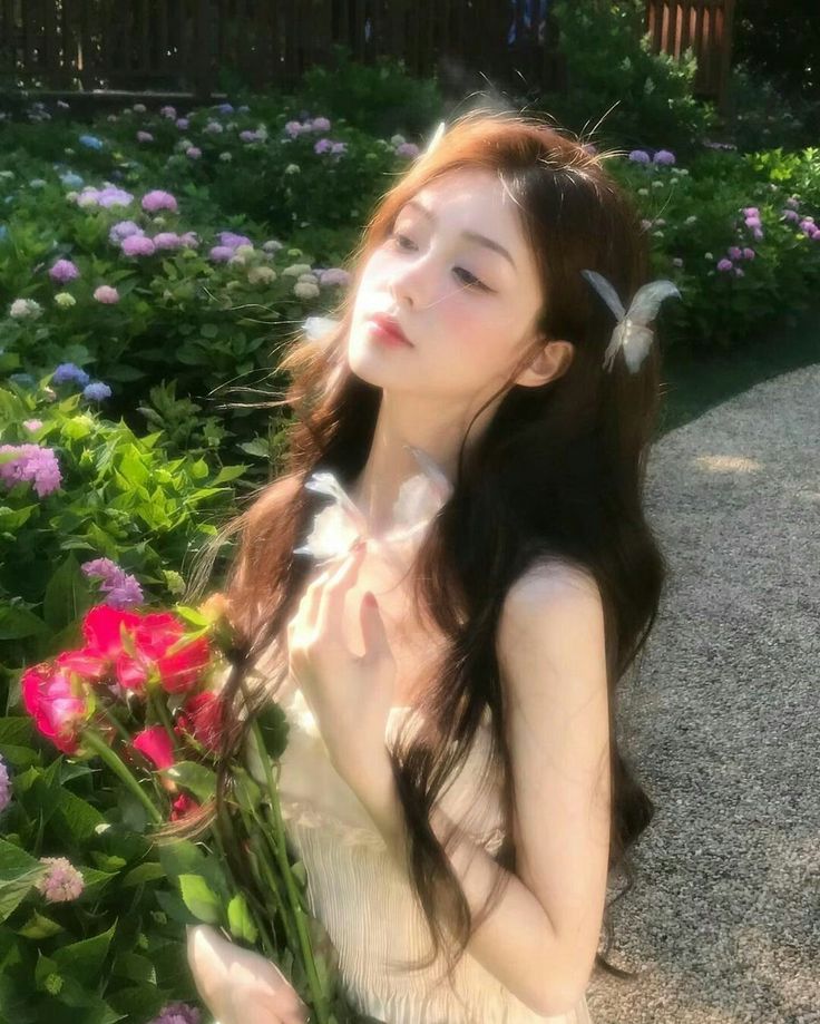 Woman with long hair and butterfly clips holding red roses in a garden