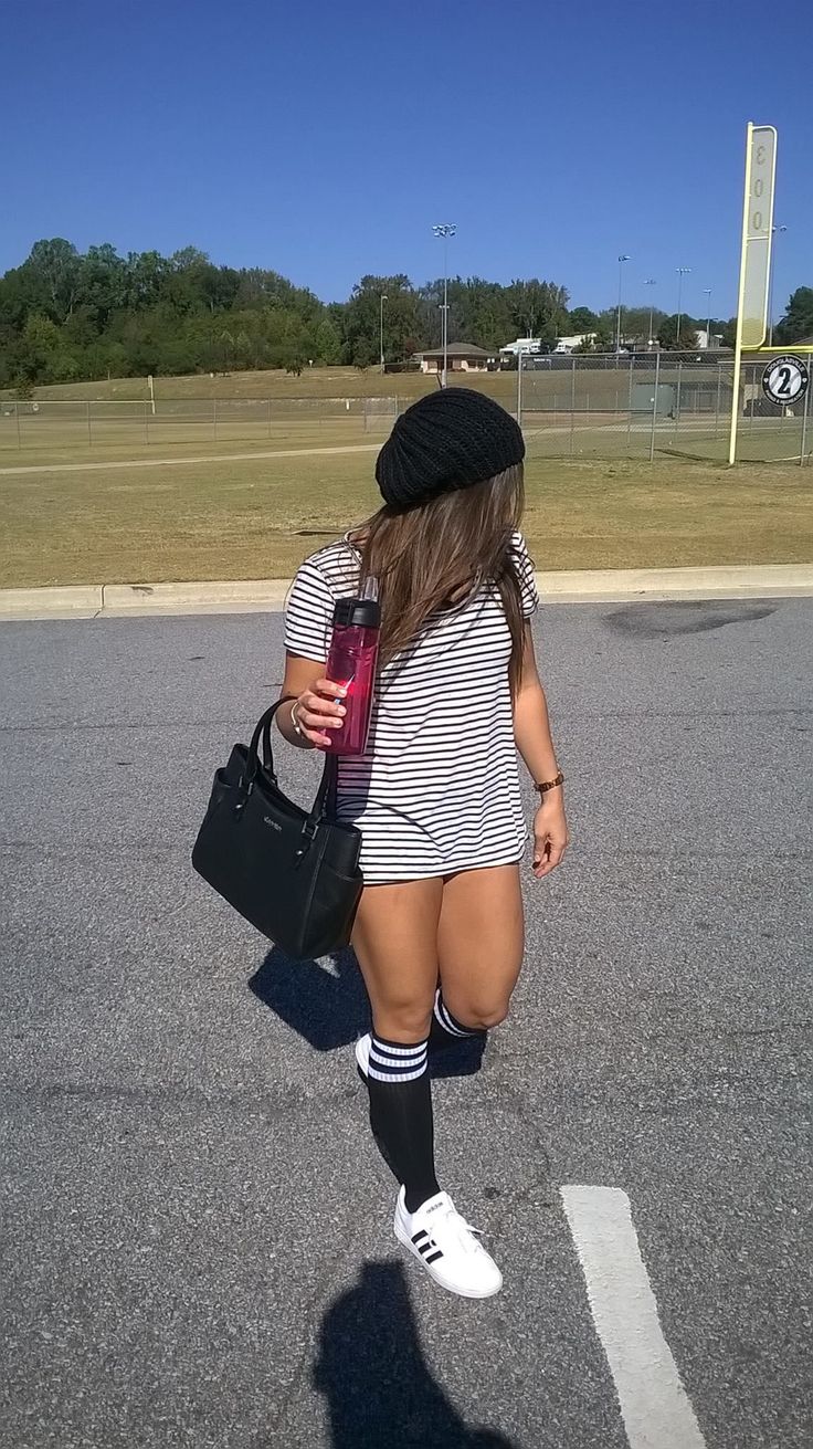 Woman in a striped shirt, black beanie, and knee high socks outdoors