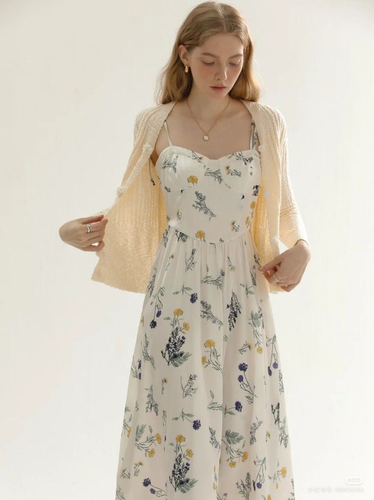 Woman in a white floral dress and a light cardigan against a white background