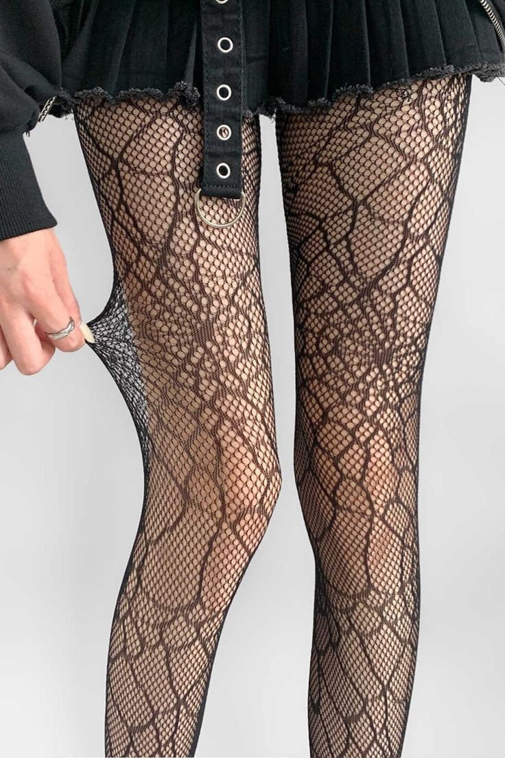 Person wearing fishnet stockings and a black skirt, pulling on the stocking