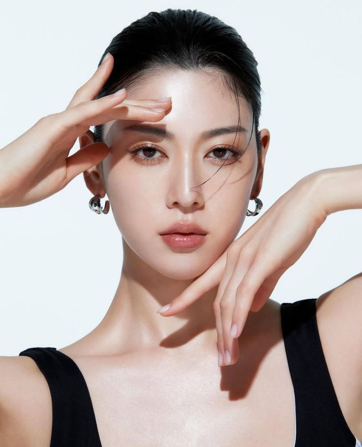 Woman with black hair and earrings posing against a white background