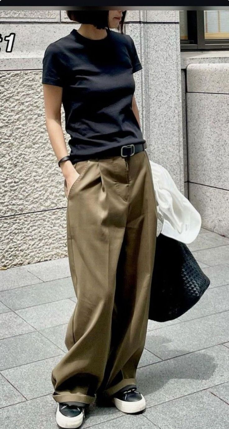 Person in a black t-shirt and wide leg pants standing outdoors