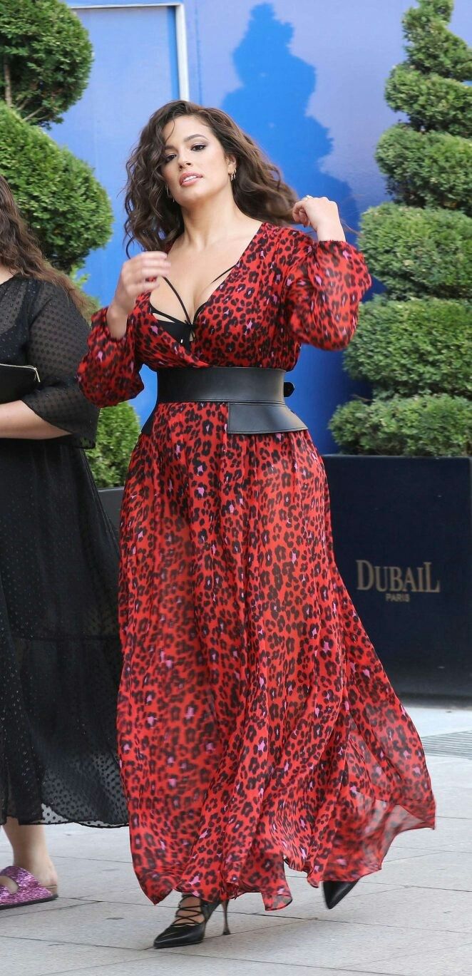 Woman in a red leopard print dress with a black corset belt and high heels