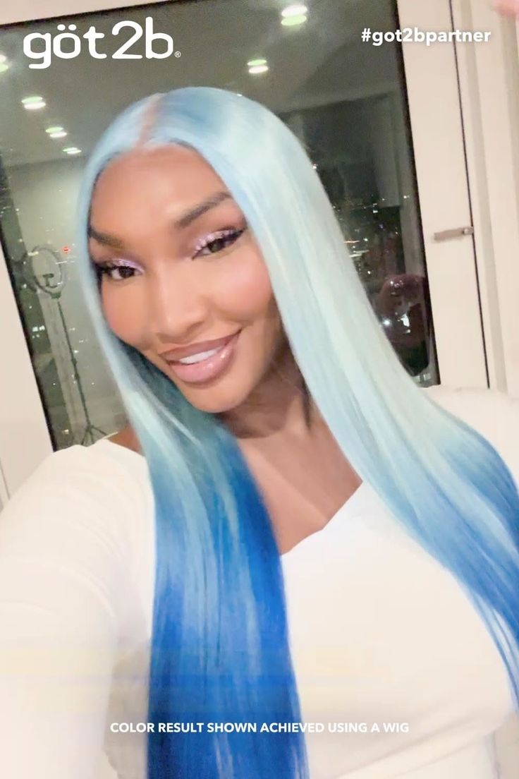 Woman with long blue ombre hair and pink eyeshadow smiling indoors