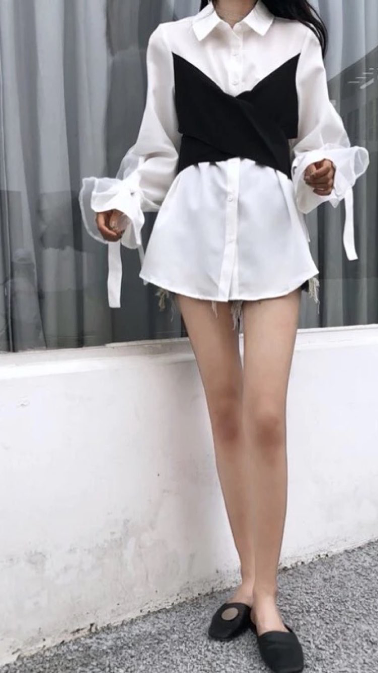 Woman in a white shirt with a black top and short shorts outdoors