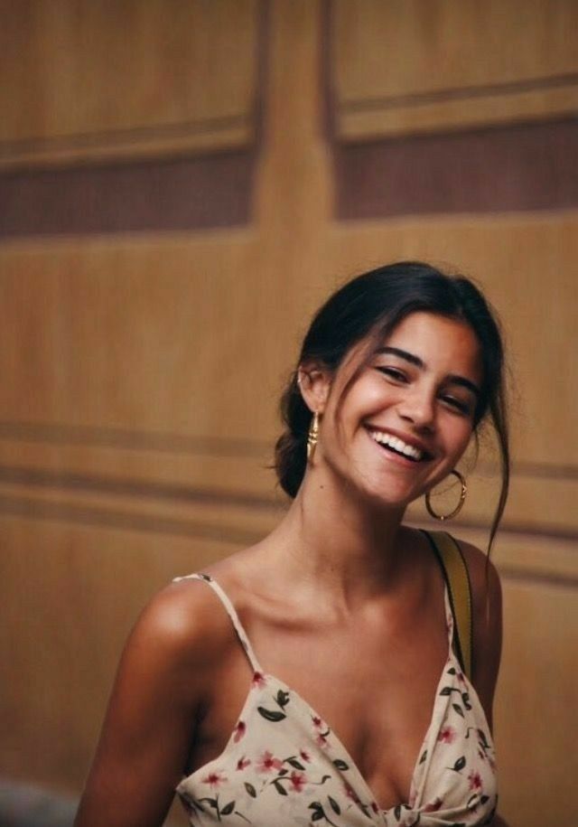 Woman with dark hair and hoop earrings wearing a floral dress, smiling