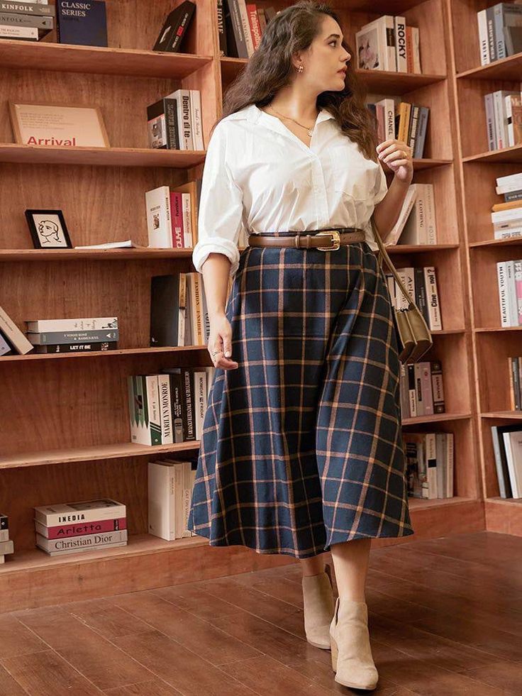 Woman in a white shirt and plaid skirt standing in front of a bookcase