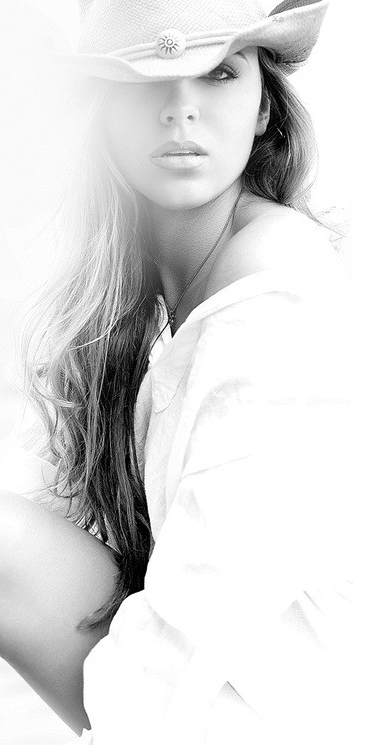 Woman in a cowboy hat and white shirt with an exposed shoulder