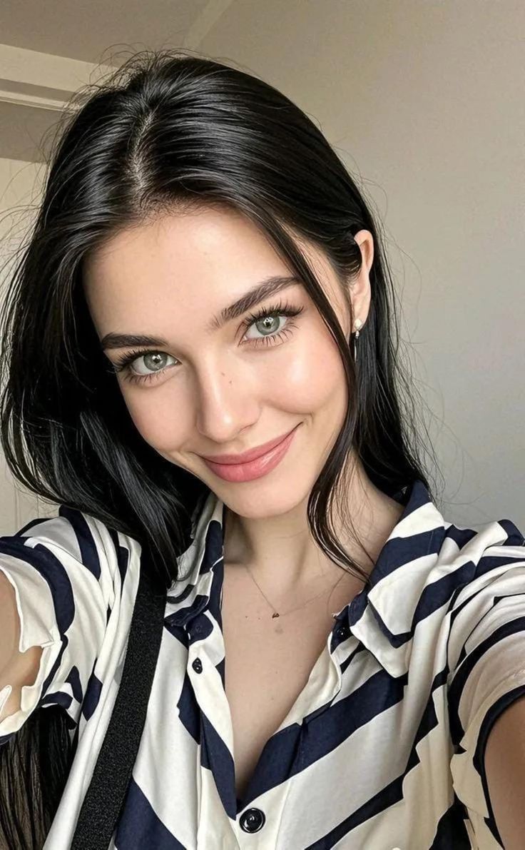 Woman with long black hair and green eyes wearing a striped shirt, smiling
