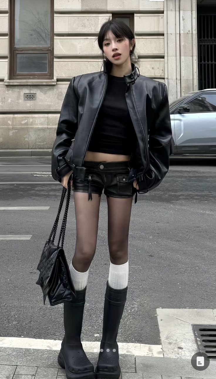 Woman in a black leather jacket and shorts on a street