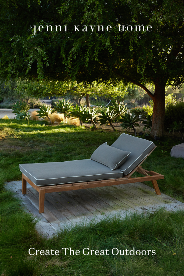Lounge chair with grey cushions on a wooden deck in a lush garden