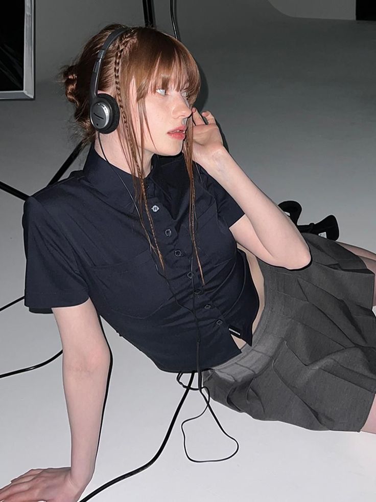 Woman with headphones and a pleated skirt lying on a white floor