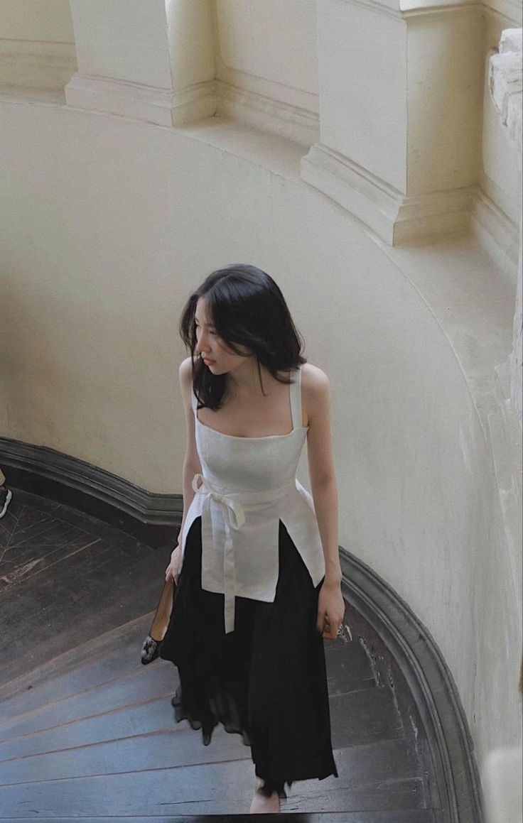 Woman in a white top and black skirt walking down a staircase