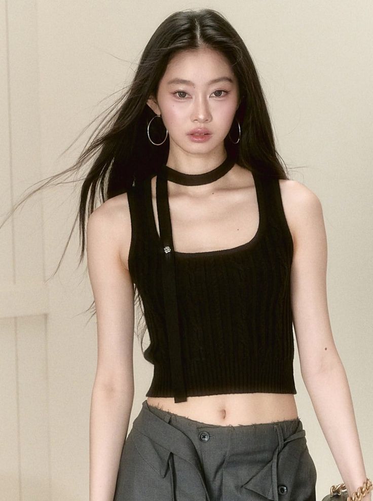 Woman with long black hair wearing a black crop top and choker in a studio