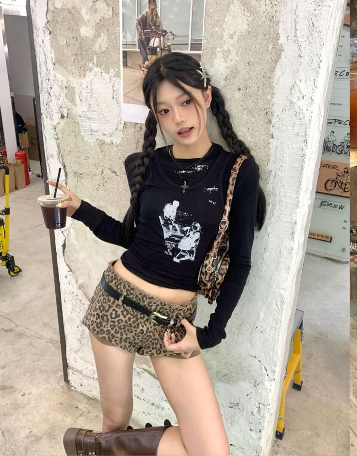 Woman with braided black hair wearing a crop top and leopard print shorts indoors