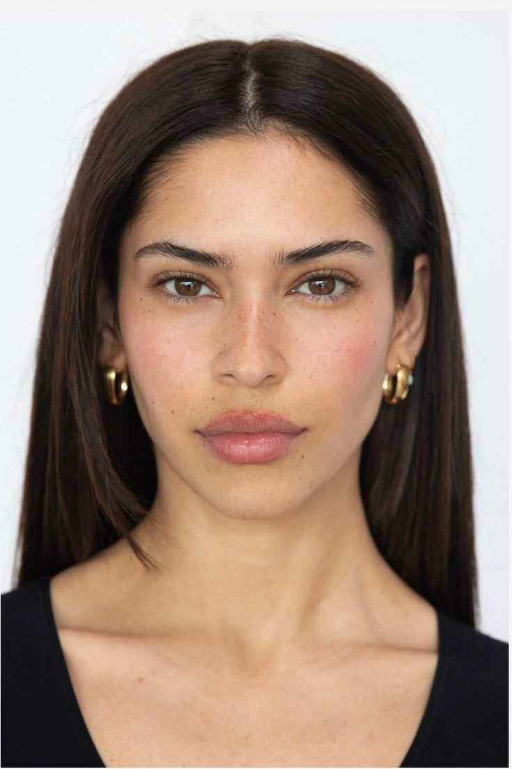 Woman with long dark hair and gold hoop earrings looking directly at the camera