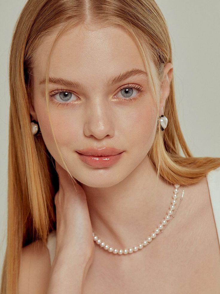 Young woman with blonde hair and blue eyes wearing pearl jewelry