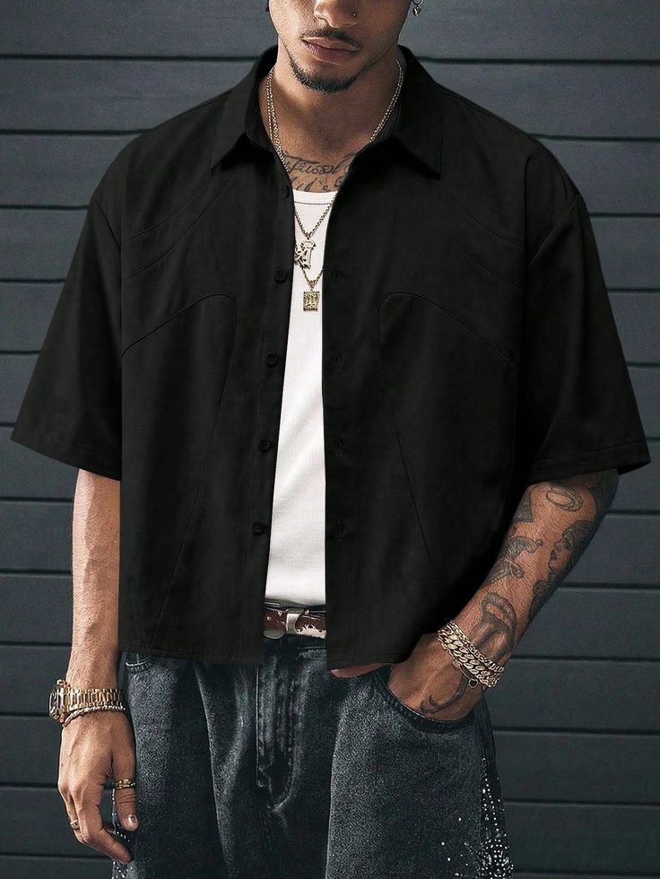 Man in a black shirt and jeans with gold chains and tattoos