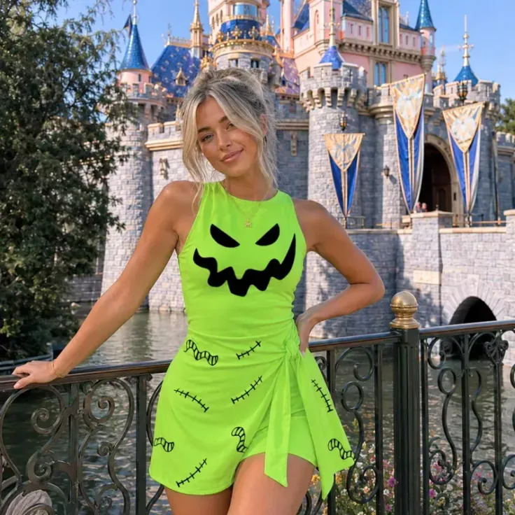Woman in a bright green outfit with a spooky face design in front of a castle